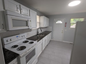 granite counters, tile flooring, subway tile backsplash and modern fixtures with a dishwasher, disposal, microwave and double sink