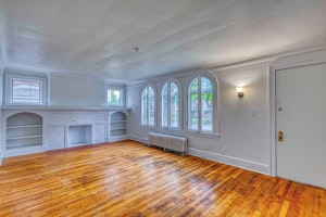 3 large beautiful ornate windows allow ample natural light to welcome you into the freshly repainted room with original hardwood flooring, decorative fireplace and built-in surrounding shelving