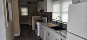 Practical kitchen featuring classic wooden cabinetry, generous counter space, and natural light—perfect for daily cooking.